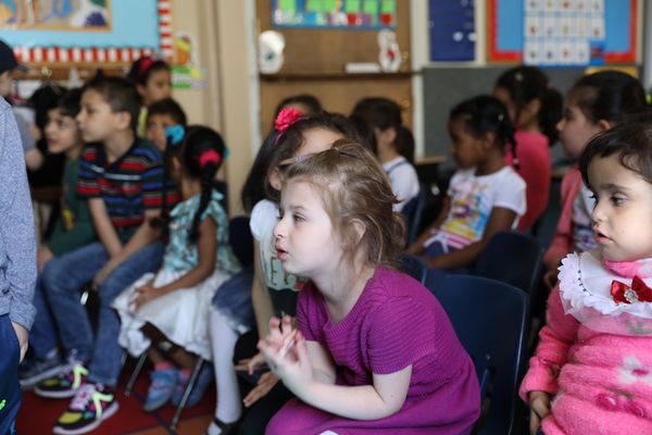 Young children seated in a classroom, listening closely